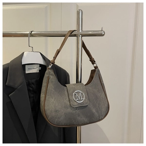 Detailed view of gray crescent bag with silver M logo and brown leather trimming