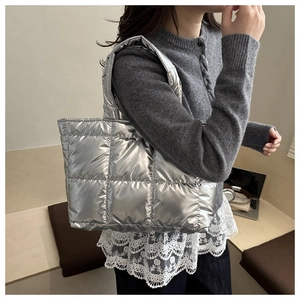Detailed view of silver quilted tote bag with metallic finish and wide shoulder straps