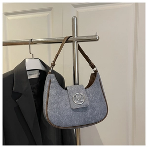 Detail of grey-blue textured hobo bag with brown leather trim and silver M logo buckle