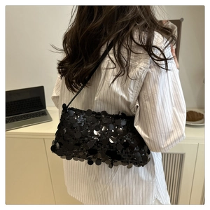 Dettaglio della borsa a spalla con paillettes nere riflettenti e tracolla sottile elegante