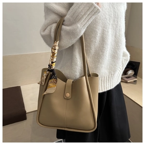 Detail of khaki bucket bag featuring a smooth leather finish and a silk scarf handle wrap