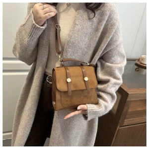 Close-up of retro brown shoulder bag with teddy bear embossing and gold metal buckles