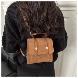 Close-up of brown suede backpack featuring retro buckle design and cartoon embossing