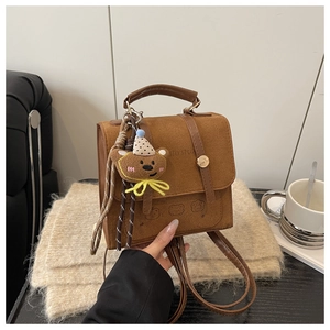 Detail of a brown vintage mini backpack with bear embroidery and teddy bear charm