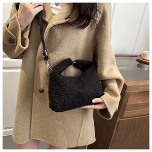 Close-up of black fuzzy faux shearling crossbody bag with adjustable shoulder strap