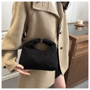 Detailed close-up of a black Sherpa fleece tote bag with detachable silver metal hooks