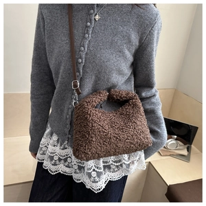 Detail of plush brown teddy fleece shoulder bag with dark leather strap and silver buckle