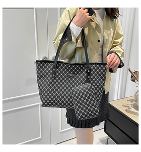 Dettaglio della borsa tote nera con motivi geometrici bianchi e targhetta logo in metallo oro