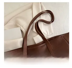 Close-up of brown leather tote bag showing fine stitching and durable shoulder straps