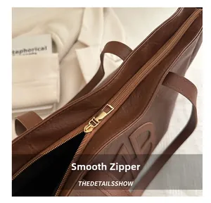 Close-up of smooth gold zipper and textured brown faux leather tote with embossed letter B