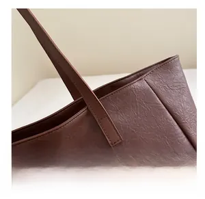 Macro detail of the neat stitching and pebbled leather texture on a dark brown tote bag