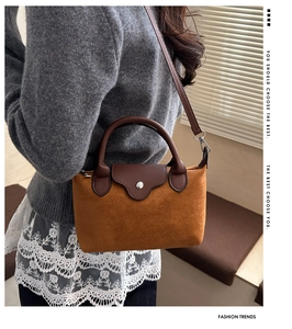 Detail of suede crossbody bag with leather handle and shoulder strap worn by a model