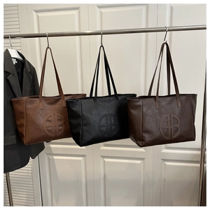 Detail view of large tote bags in brown, black, and dark coffee with embossed logo