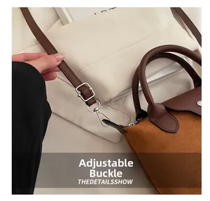 Detail of adjustable leather strap and silver metal buckle on brown suede handbag