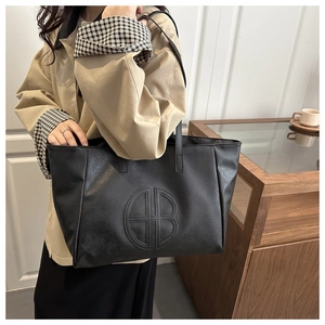 Macro detail of black PU leather tote bag with geometric embossed logo and grainy texture