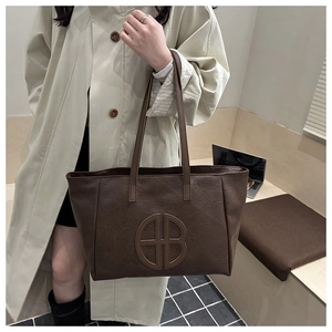 Detail of dark brown faux leather tote bag with large logo and laptop for work use