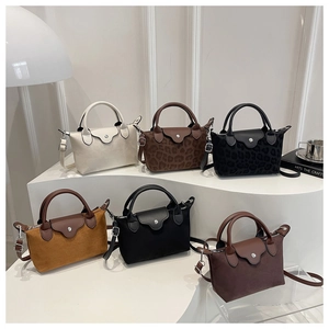 Close-up of minimalist nylon handbags with leather handles and metallic snap closures