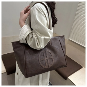 Detail of a brown lychee pattern leather tote bag with HB logo patch and shoulder straps