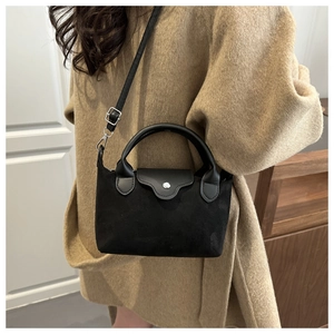 Detail of a black nylon dumpling bag featuring a curved leather handle and matte texture