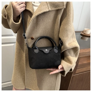 Detail of black mini crossbody bag featuring suede texture and silver metal buckle
