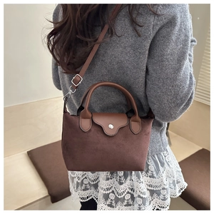 Close-up of brown suede mini bag with leather trim and silver metal zipper detail