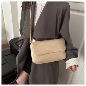 Detail of beige suede crossbody bag with gold chain strap on a trench coat model