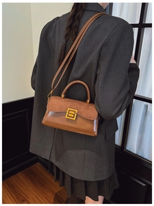Brown retro shoulder bag with gold clasp shown on a model in a grey blazer suit