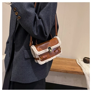 Detail view of brown faux leather and white shearling baguette bag worn by a model