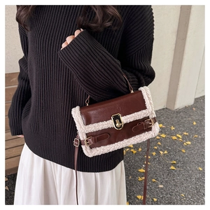 Close-up of brown leather bag with white sherpa trim and golden metal twist lock