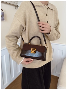 Detail of vintage brown shoulder bag with gold clasp and mixed leather textures