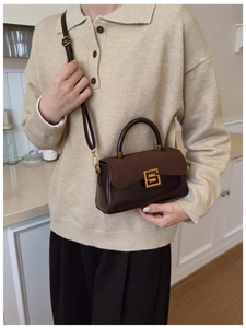 Detail of retro brown patchwork handbag with gold square buckle worn by a model