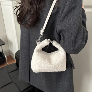 Chic white faux shearling tote bag with leather strap shown as crossbody style