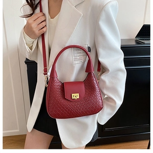 Detail of red woven leather shoulder bag with gold square buckle and adjustable strap