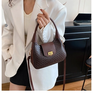 Detail of dark brown woven crescent bag with gold buckle and smooth leather flap