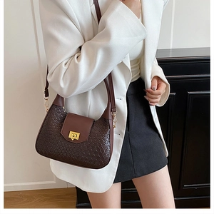 Detail of dark brown woven texture underarm bag with elegant golden metallic twist lock