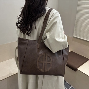 Minimalist brown vintage tote bag with large capacity shown on shoulder in daily use