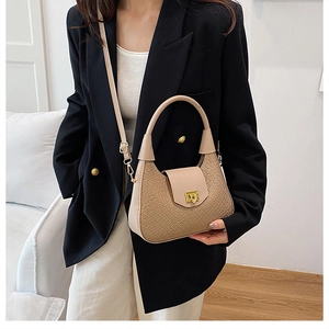 Detail view of beige half-moon handbag featuring woven texture and gold square lock closure