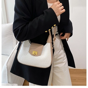 Detail of checkered texture and golden buckle on crescent shoulder bag worn with blazer