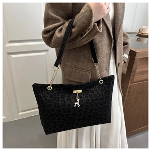 Detail of leopard print tote bag with gold chain strap and deer charm on a model