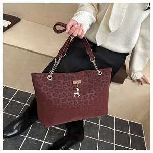 Close-up of leopard print faux suede tote with gold deer charm and chain strap