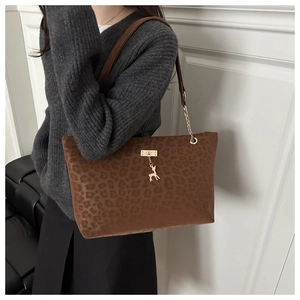 Detail of leopard print tote bag with golden deer pendant and chain strap on shoulder