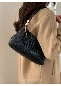 Détail du sac à bandoulière en cuir tressé noir montrant la texture et le cordon crème