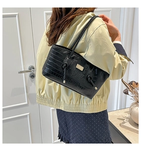 Close-up of black crocodile pattern leather texture with gold metal buckle detail on bag