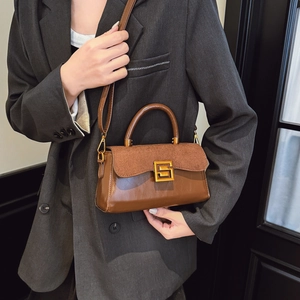 Brown leather crossbody bag with gold metal buckle on a model in grey suit