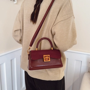 Burgundy faux leather square handbag with gold buckle and top handle shown on model