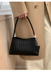 Détail d'un sac à main en cuir tressé noir avec pompon noué et texture fine