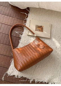 Vue de dessus d'un sac hobo en cuir tressé marron avec nœuds sur un tapis texturé