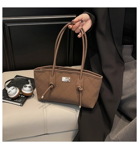 Detail of dark brown quilted tote bag with silver hardware and knotted handle accents