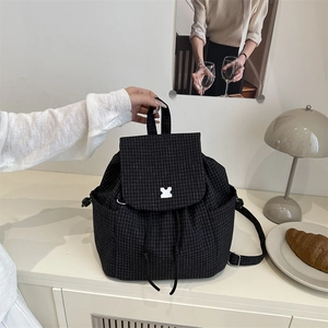 Black checkered drawstring backpack with puzzle charm in a modern lifestyle setting