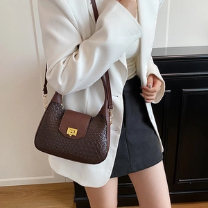 Deep brown crescent hobo bag with woven texture and gold clasp on elegant female model